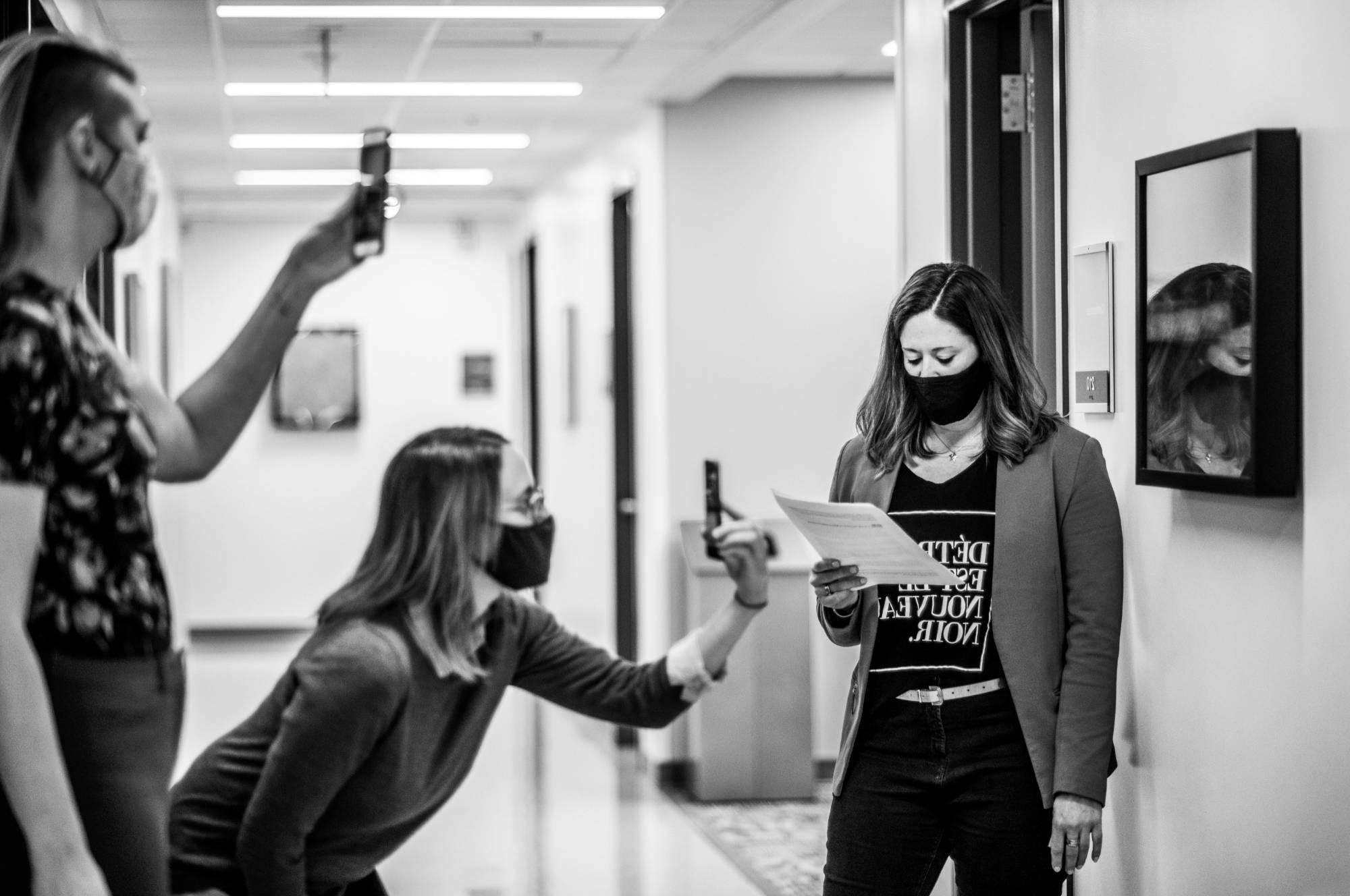 Two students take photos of another student using their phones